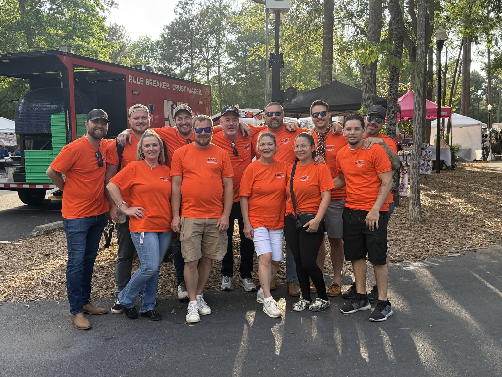The Sharpvue team and festival committee in matching orange shirts at the Sharpvue Irmo International Festival