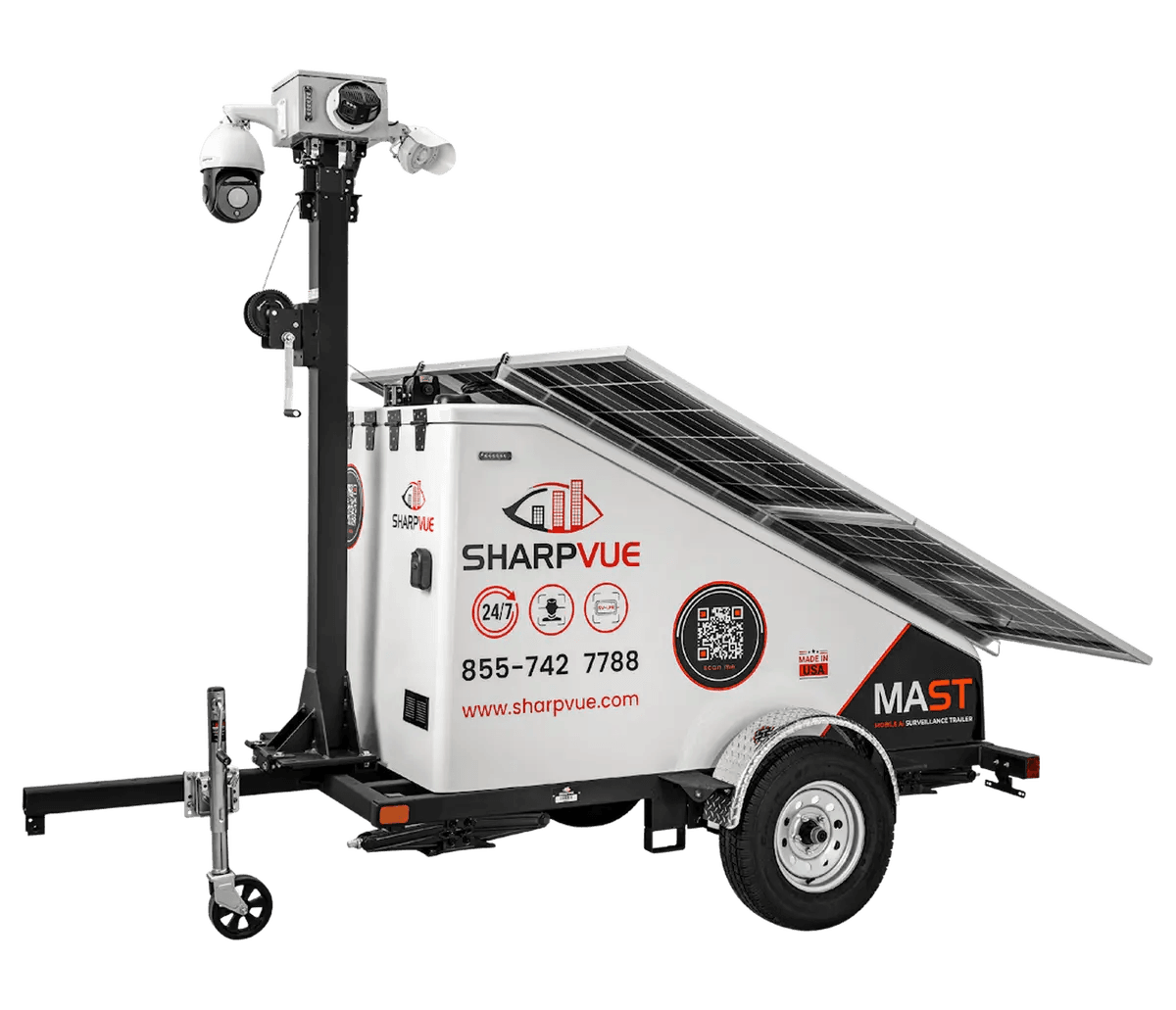 The Sharpvue MAST — a white solar surveillance trailer with a tilted panel array, Sharpvue branding on the enclosure, and a black mast carrying a PTZ dome, an infrared bullet camera, and a strobe speaker.